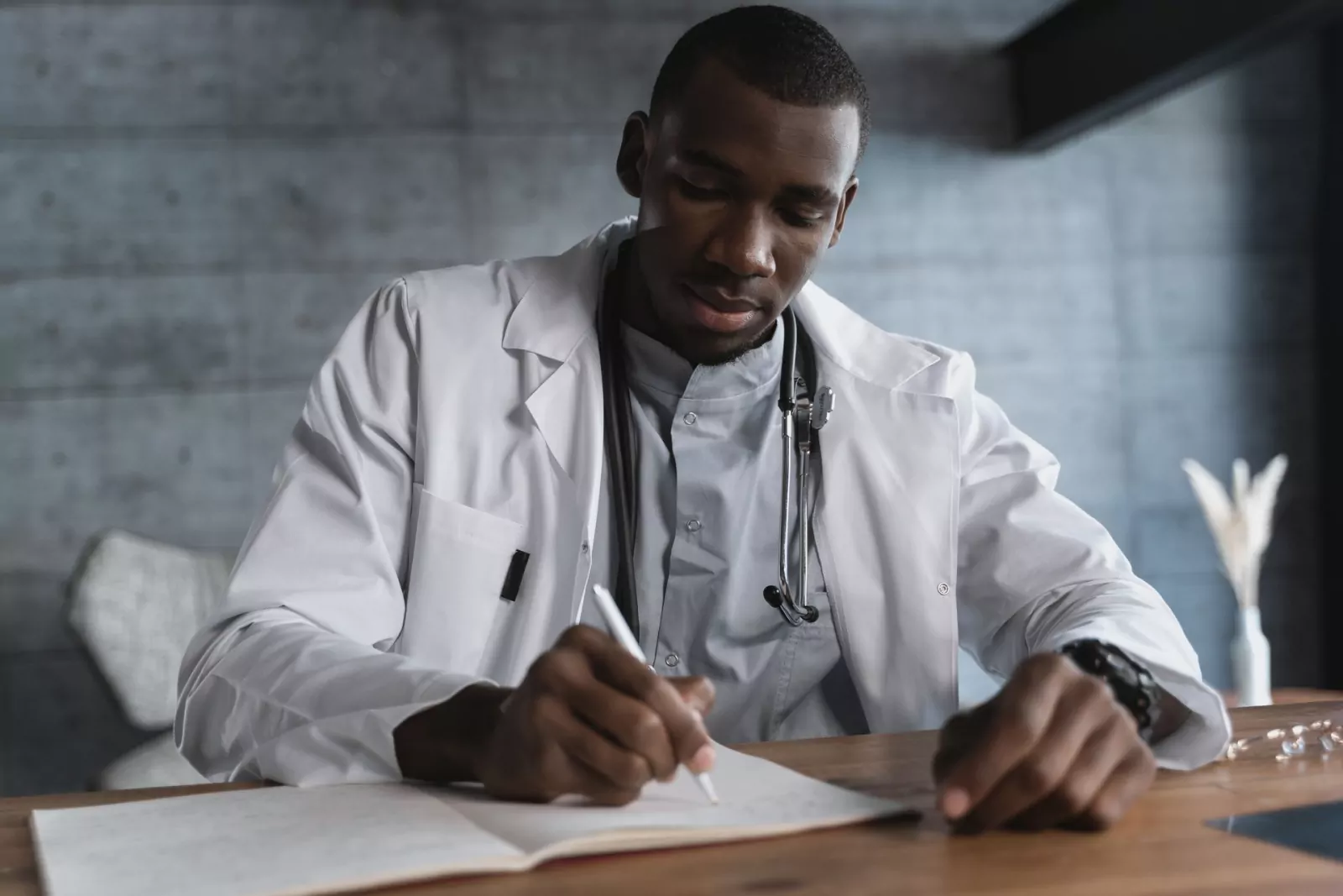A clinician in a white lab coat reviewing notes at a desk
